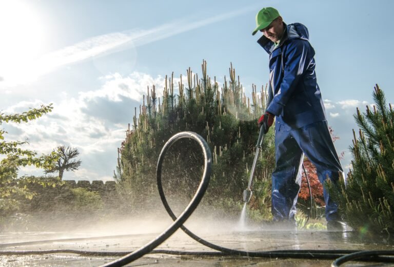 Garden Washing Maintenance. Caucasian Worker in His 30s with Pressure Washer Cleaning Brick Paths.