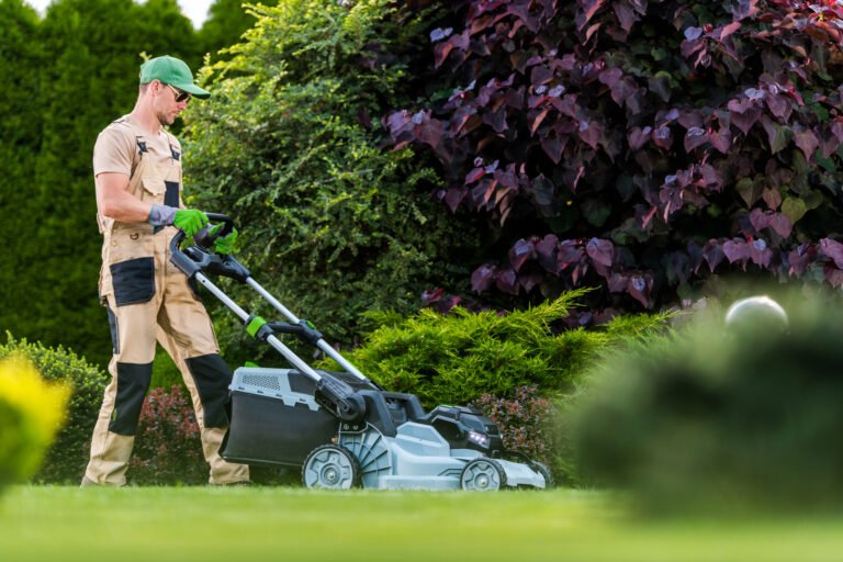 A skilled gardener trims the grass in a lush garden filled with green shrubs and colorful plants on a bright afternoon, ensuring a neat appearance.
