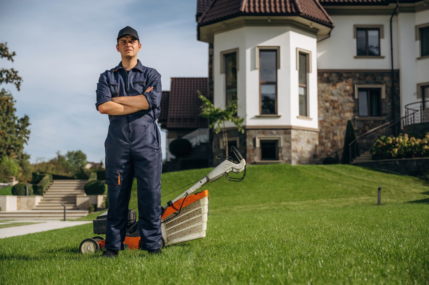 Standing with arms crossed. Professional gardener is on the lawn.